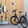 Ein modernes E-Bike steht in einer Garage neben einer Ladestation an einer Holzwand.