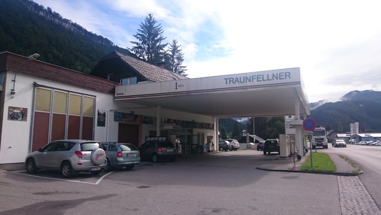 Eine Tankstelle mit dem Namen Traunfellner in einer ländlichen Umgebung mit Bergen im Hintergrund.