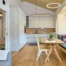 Moderne K&uuml;che mit Holz- und Betonoptik, Esstisch und Sitzbank am Fenster.