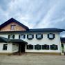 A traditional two-story farmhouse with white walls and black shutters.