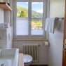 A modern bathroom with a window overlooking a green landscape.