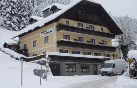 A snow-covered building with the inscription 'Pension Panorama' in a wintry landscape.