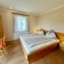 A cozy bedroom with wooden furniture, a double bed, and a desk.