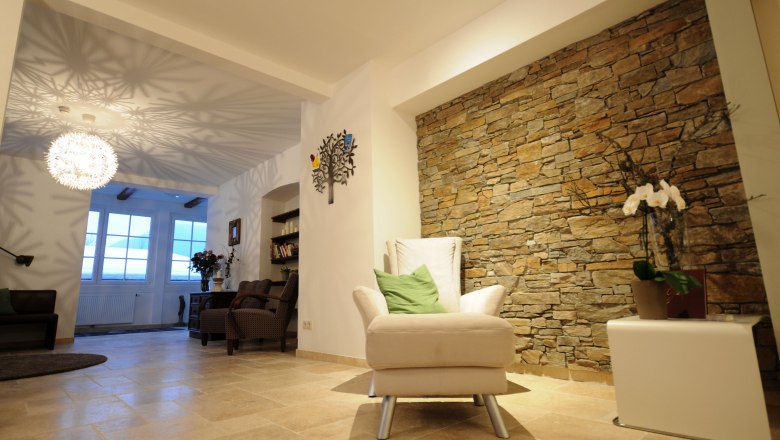 Gemütlicher Raum mit Steinwand, Sessel und dekorativer Lampe.