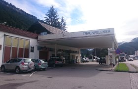 Eine Tankstelle mit dem Namen Traunfellner in einer l&auml;ndlichen Umgebung mit Bergen im Hintergrund.