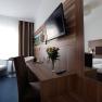 Modern eingerichtetes Hotelzimmer mit Doppelbett, Schreibtisch, Flachbildfernseher und Blumenstrau&szlig;.