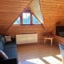 A cozy living room in an attic apartment with wood paneling, a sofa, a TV, and a skylight.