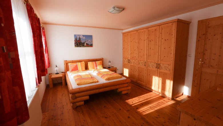 Bedroom with wooden furniture, double bed and closet.