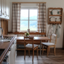 A cozy kitchen with wooden furniture and a view of the mountains through the window.