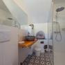 Modern bathroom with glass shower, stone washbasin and patterned floor.