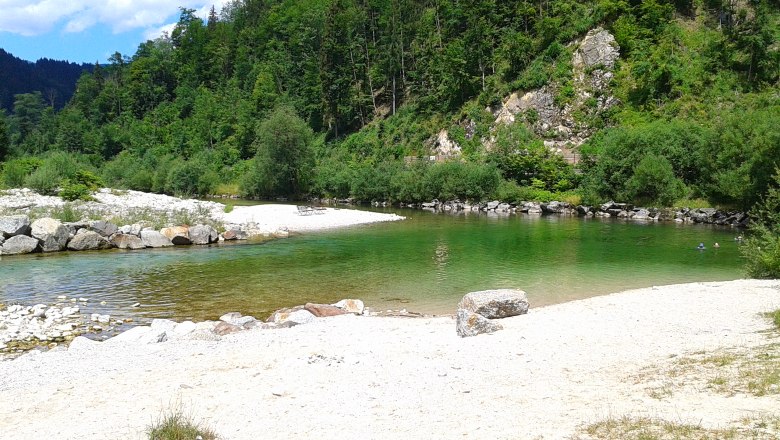 Flussbad an der Ybbs mit gr&uuml;nem Wasser und Kiesstrand, umgeben von bewaldeten H&uuml;geln.