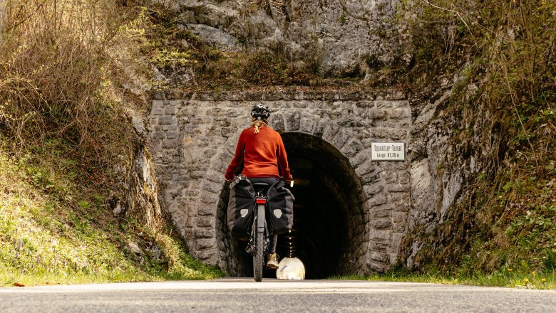Ein Radfahrer genie&szlig;t die frische Bergluft und die atemberaubende Natur, w&auml;hrend er auf dem Ybbstalradweg in die Tiefe eines alten Tunnels f&auml;hrt. Umgeben von &uuml;ppigem Gr&uuml;n und majest&auml;tischen Felsen, wird die Fahrt zu einem unvergesslichen Erlebnis in der idyllischen Landschaft des Mostviertels.