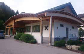 Geb&auml;ude der Raiffeisenbank mit Holzverkleidung und geschwungenem Dach.