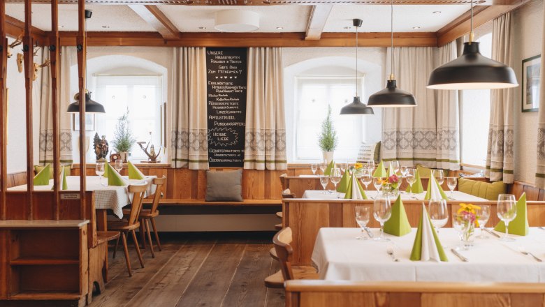 Cozy, traditional dining room with wooden furniture, laid tables and green napkins.