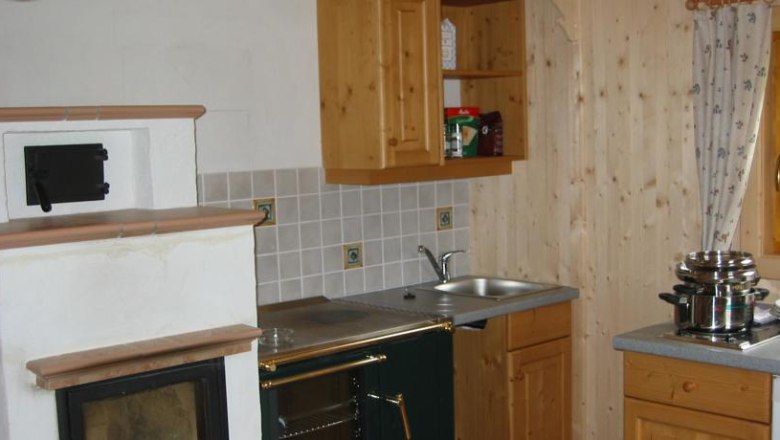 K&uuml;che in einem rustikalen Stil mit Holzschr&auml;nken, einem Ofen und einem Herd.