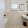 Modernes Badezimmer mit Fenster, Doppelwaschbecken und Badewanne.
