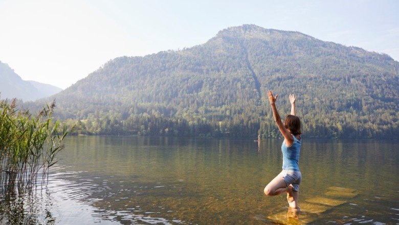 Eine Frau macht Yoga in einem See mit einem Berg im Hintergrund.