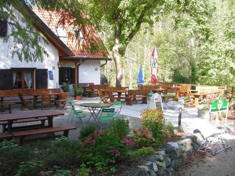 Außenbereich der Schindlhütte mit Tischen und Stühlen im Grünen.