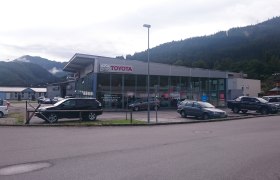 Autohaus Rottner mit Toyota-Logo und mehreren geparkten Autos vor einem Gebäude in einer bergigen Landschaft.
