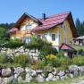 Yellow house with a red roof in a green landscape.