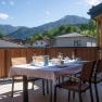 Ein gedeckter Tisch auf einer Terrasse mit Blick auf Berge und H&auml;user.
