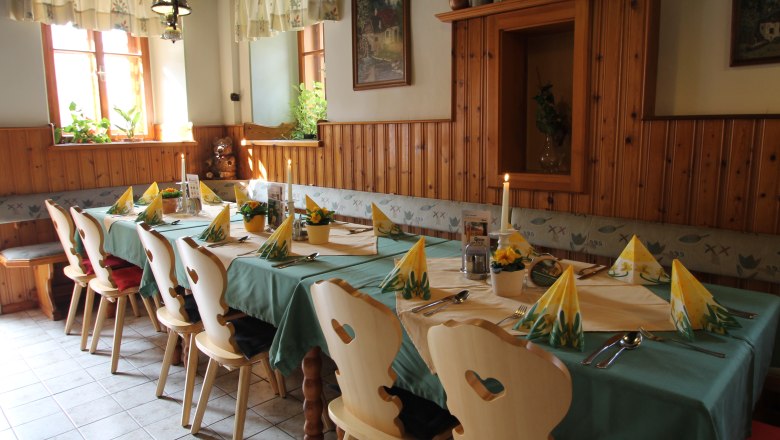 Gemütliche Gaststube mit gedecktem Tisch, Holzstühlen und Dekoration.