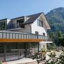 Modernes Haus mit Berg im Hintergrund an einem sonnigen Tag.
