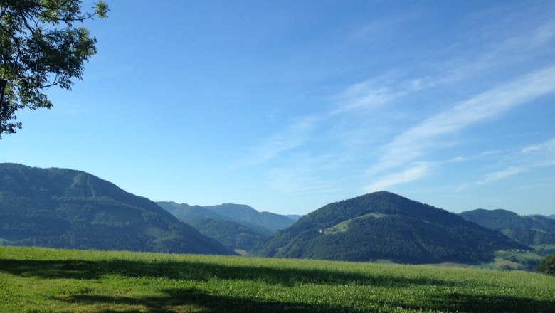 Landschaft mit grünen Hügeln und blauem Himmel.