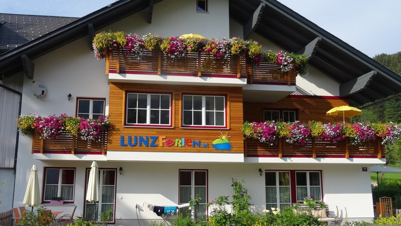 Lunz Vacation, Geli Mayr, © zVg A vacation home with colorful flowers on the balconies and the lettering 'LUNZ Ferien'.