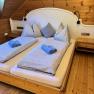 Gem&uuml;tliches Schlafzimmer mit Holzw&auml;nden und einem Doppelbett, das mit blauen Handt&uuml;chern und gestreifter Bettw&auml;sche dekoriert ist.
