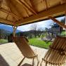 View from a wooden pavilion of a mountain landscape with a swing and slide in the garden.