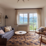 Cozy living room with a sofa, armchairs, and a large window offering a view of the mountains.