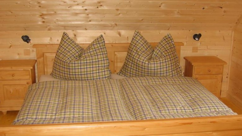 Holzschlafzimmer mit kariertem Doppelbett und Nachttischen.