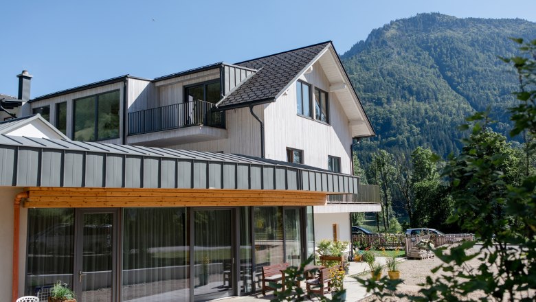 Modernes Haus mit Berg im Hintergrund an einem sonnigen Tag.