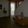 Innenansicht eines Wohnbereichs mit Holzkiste, Pflanze und Treppe.