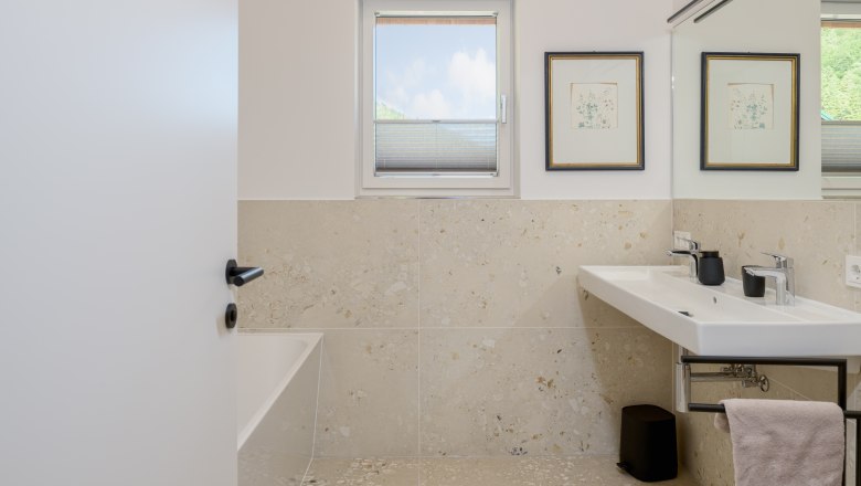 Modernes Badezimmer mit Fenster, Doppelwaschbecken und Badewanne.