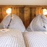 Gemütliches Schlafzimmer mit karierten Bettdecken und Holzvertäfelung.