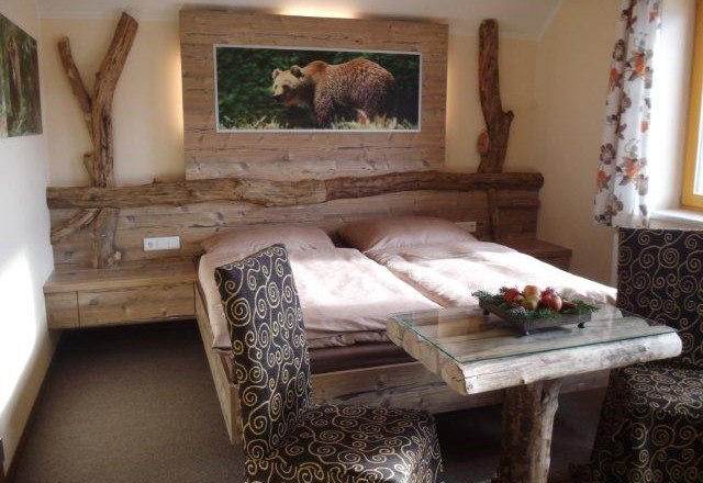 Rustikales Schlafzimmer mit Holzmöbeln und Bärenbild an der Wand.