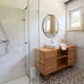 Modern bathroom with a shower, sink, and wooden cabinet.