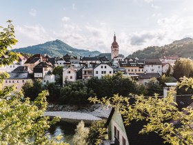 The picture shows Waidhofen an der Ybbs. A high church tower and the Mostviertel mountain area can be seen in the background.