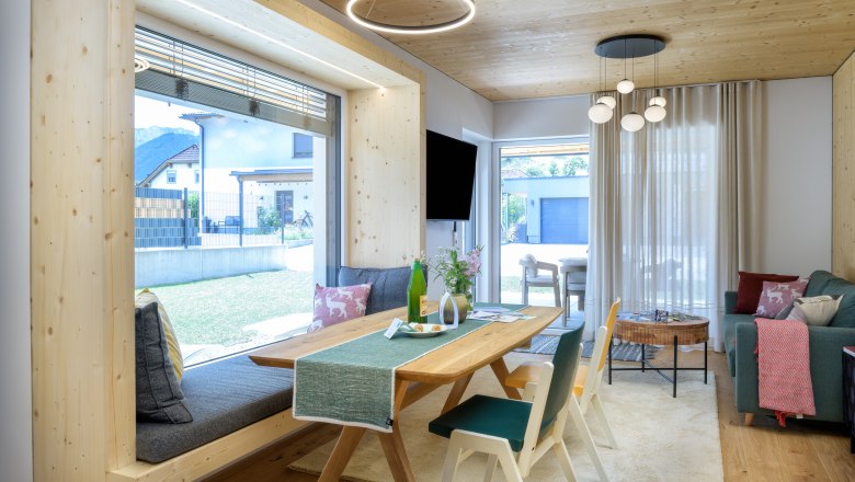 Modernes Wohnzimmer mit Holzelementen, gro&szlig;em Fenster und stilvoller Einrichtung.