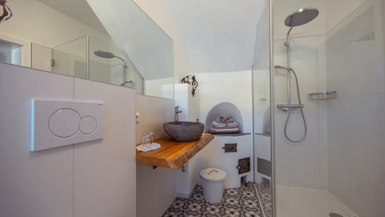 Modern bathroom with glass shower, stone washbasin and patterned floor.