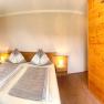 Cozy bedroom with a double bed, wooden furniture, and an adjoining bathroom with a shower.