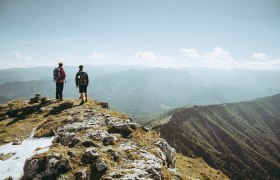 Zwei Wanderer stehen am Gipfel und genie&szlig;en den atemberaubenden Blick &uuml;ber die Ybbstaler Alpen. Die frische Bergluft und die majest&auml;tischen Landschaften laden dazu ein, die Seele baumeln zu lassen und die Sch&ouml;nheit der Natur zu erleben.