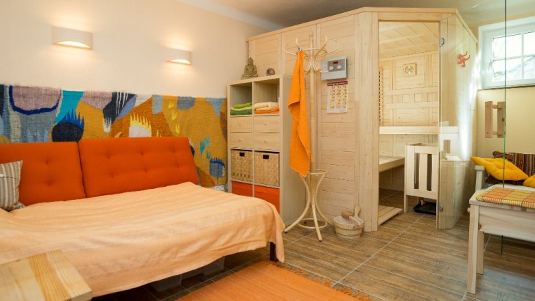 Cozy living room with sauna, sofa and colorful wall decorations.