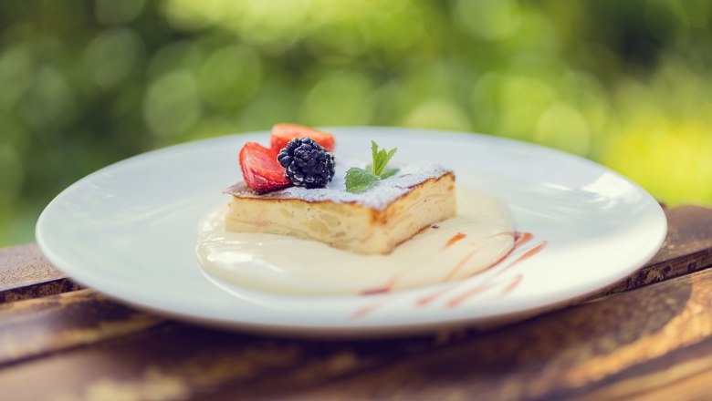 Ein Dessert mit Beeren auf einem Teller im Freien.