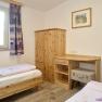 Children's room with two single beds, wooden furniture and a window with purple curtains.
