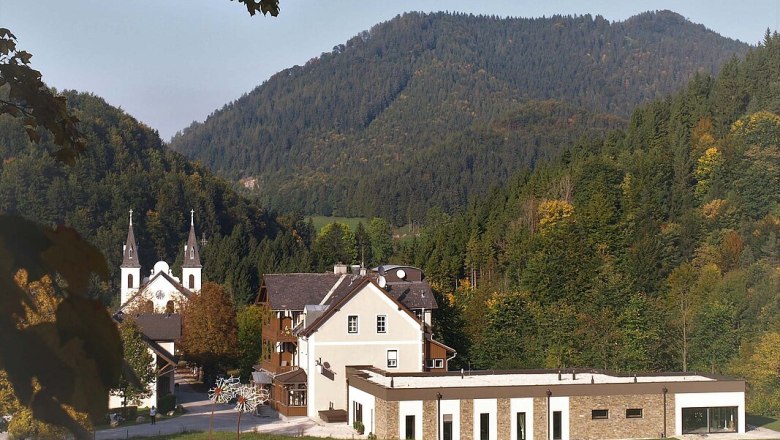 Geb&auml;ude des Fastenhauses Maria Seesal vor bewaldeten H&uuml;geln.
