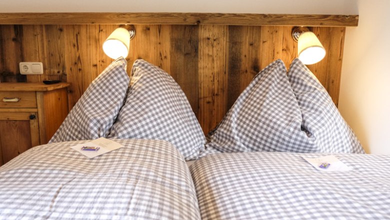 Cozy bedroom with checkered bedspreads and wood paneling.